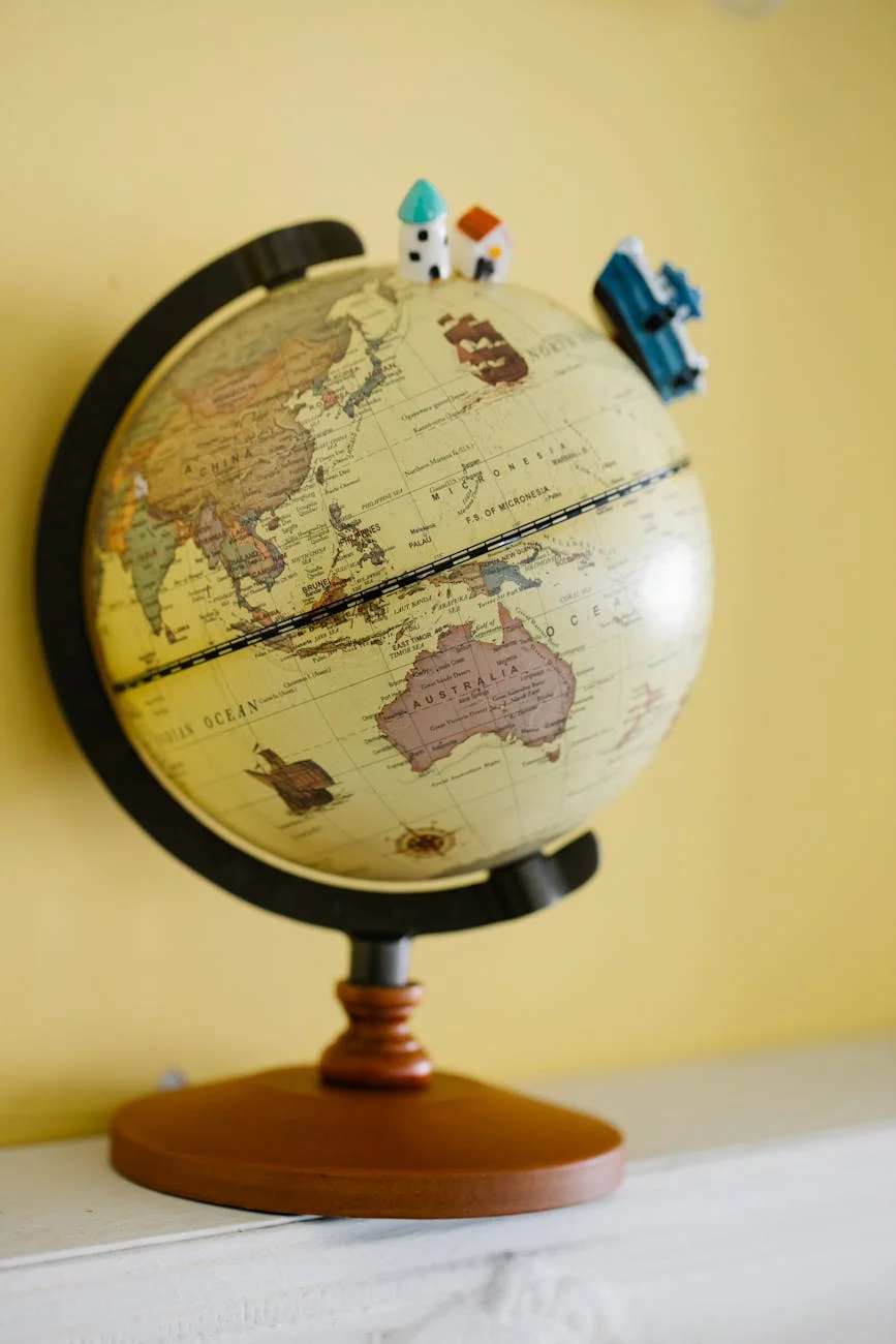 A vintage globe featuring miniature houses and a train, symbolizing global travel and exploration.