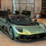Aston Martin Valhalla Verdejant Jade exposto em showroom, vista três-quartos frontal destacando fibra de carbono e detalhes aerodinâmicos