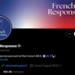 Smartphone exibindo o perfil 'French Response' no X com bandeira francesa desfocada ao fundo
