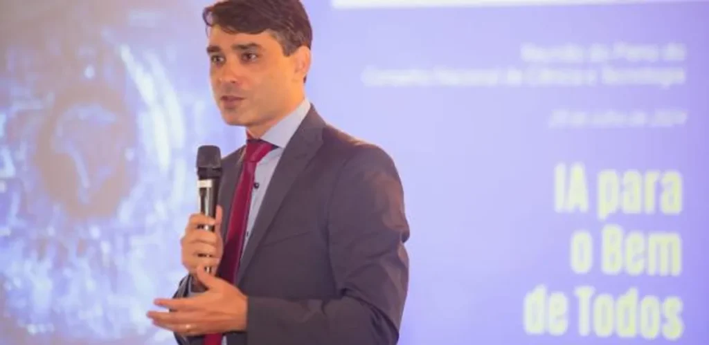 ‘Há quem defenda que o Brasil só importe tecnologia’, diz diretor do MCTI 1 Hugo Valadares, diretor do MCTI, discursando em evento oficial com bandeira do Brasil ao fundo.