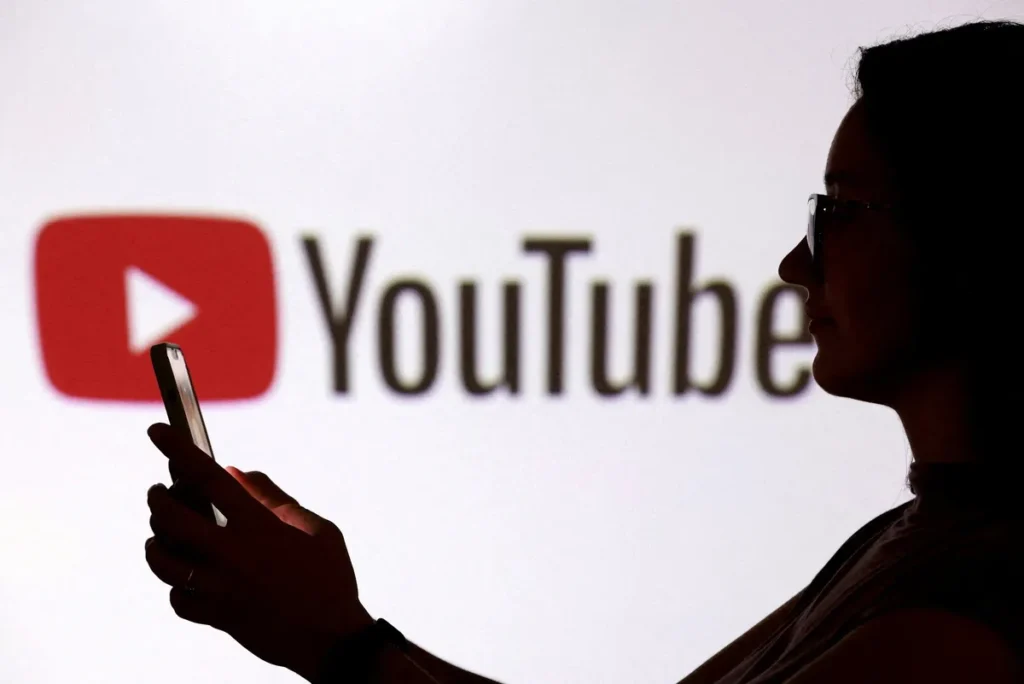 Smartphone com tela do YouTube em primeiro plano e silhueta de adolescente desfocada ao fundo, com sobreposição de gráficos de IA.
